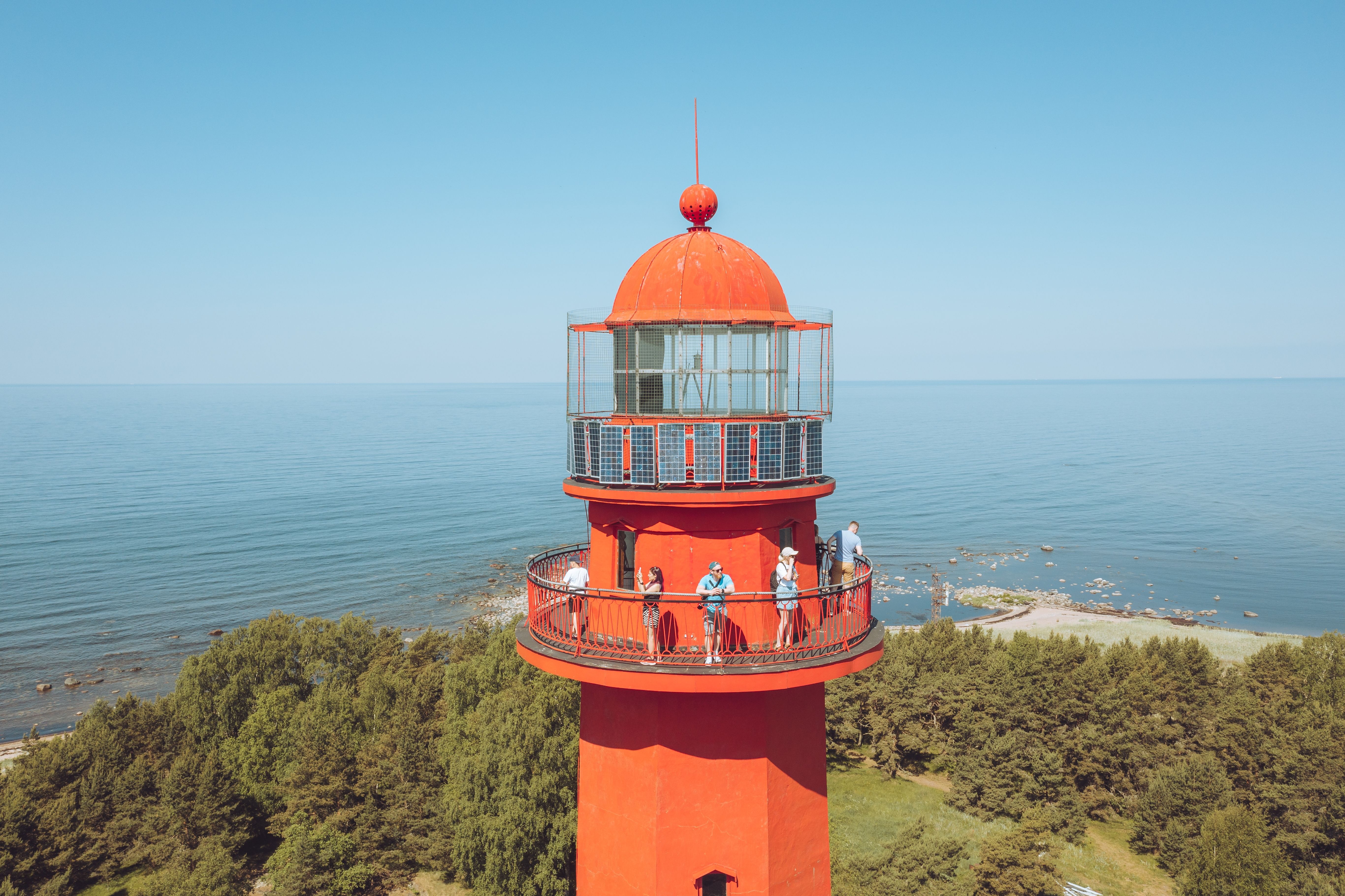 People on the viewing platform of an orange lighthouse on Naissaar island in Estonia